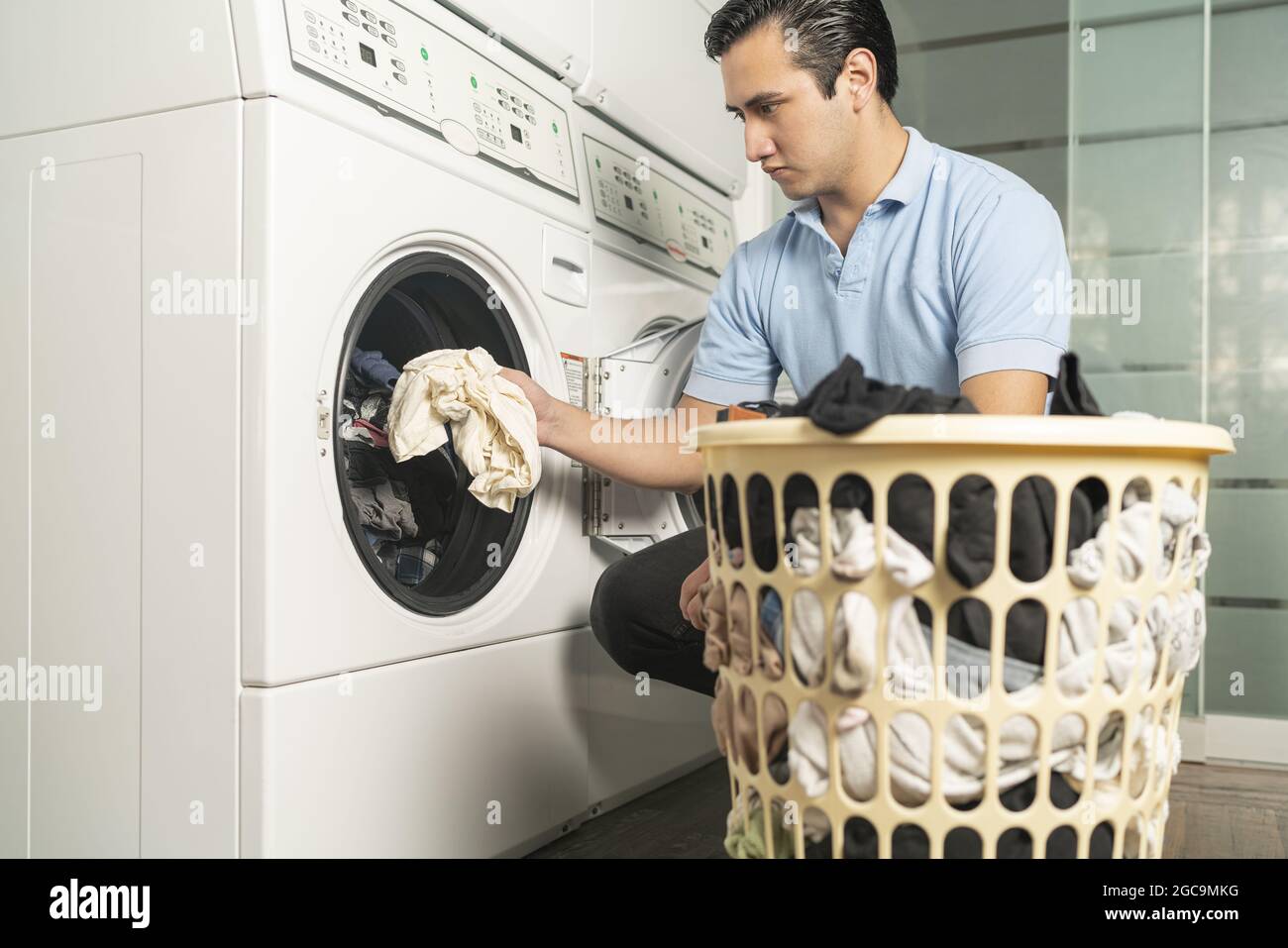 Laundry worker putting clothes out of a basket in a washing machine