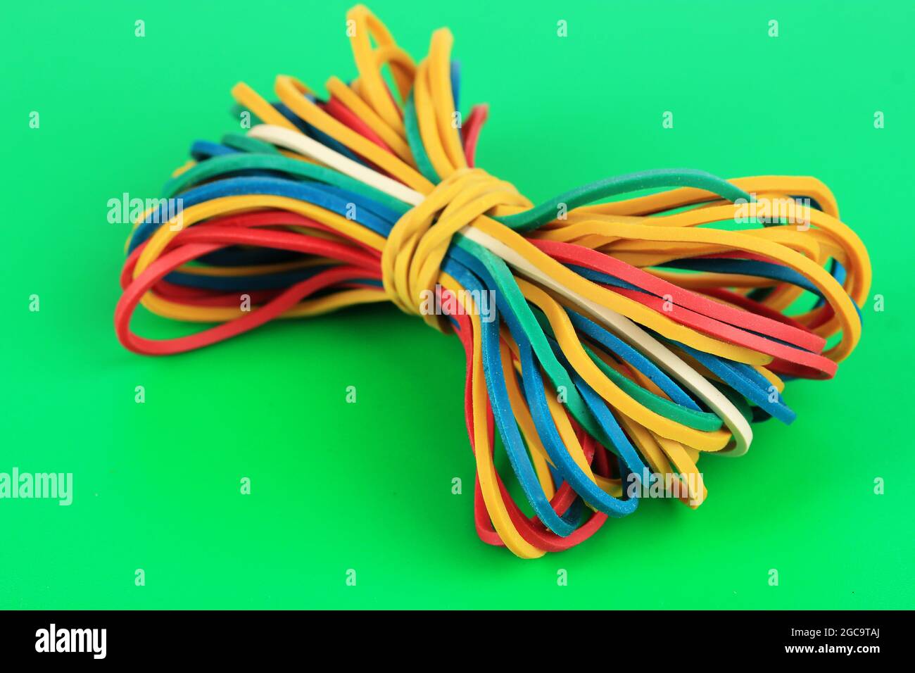 Colorful rubber bands on green background Stock Photo by