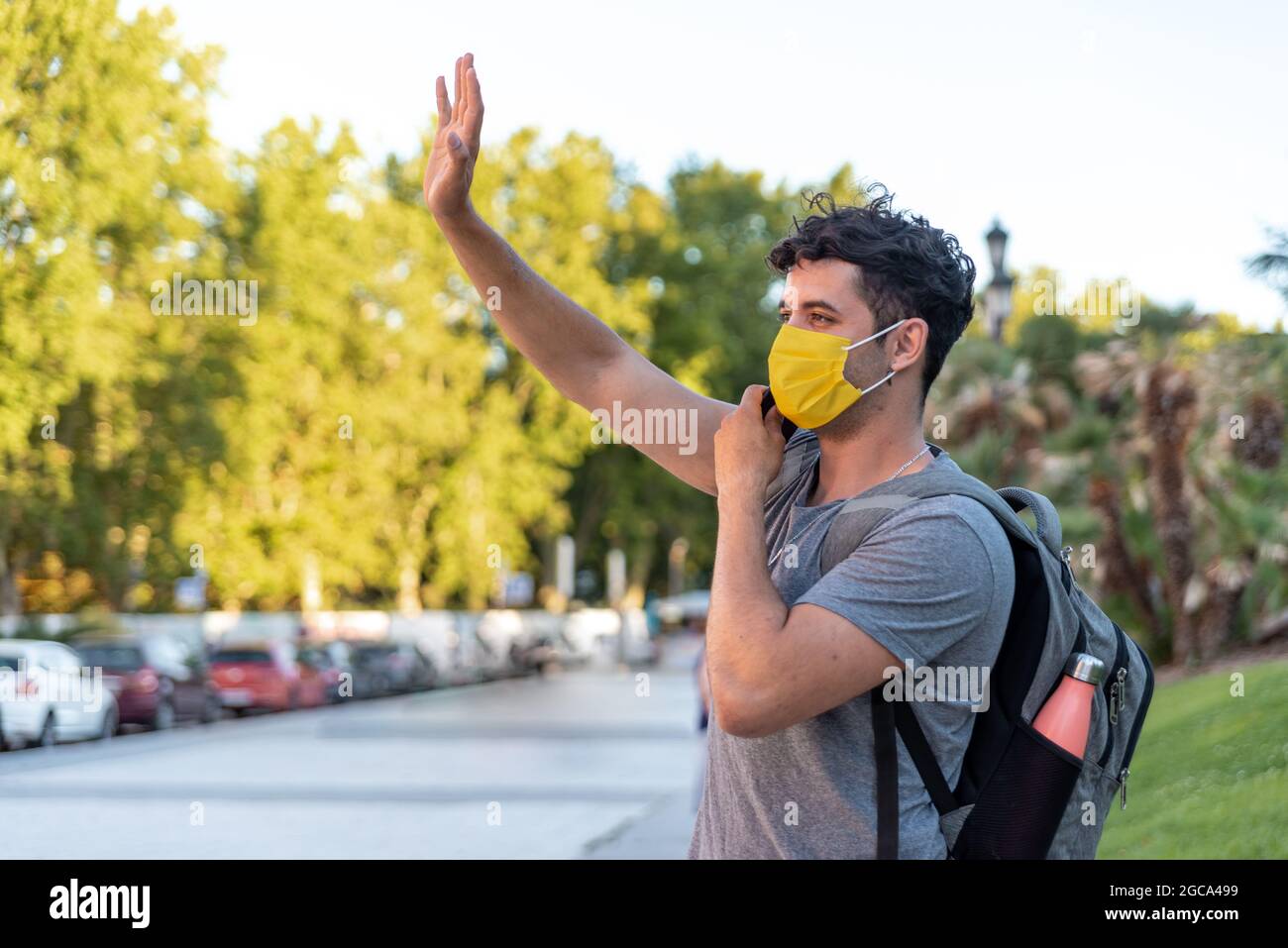 Young latin man with face mask using phone Stock Photo