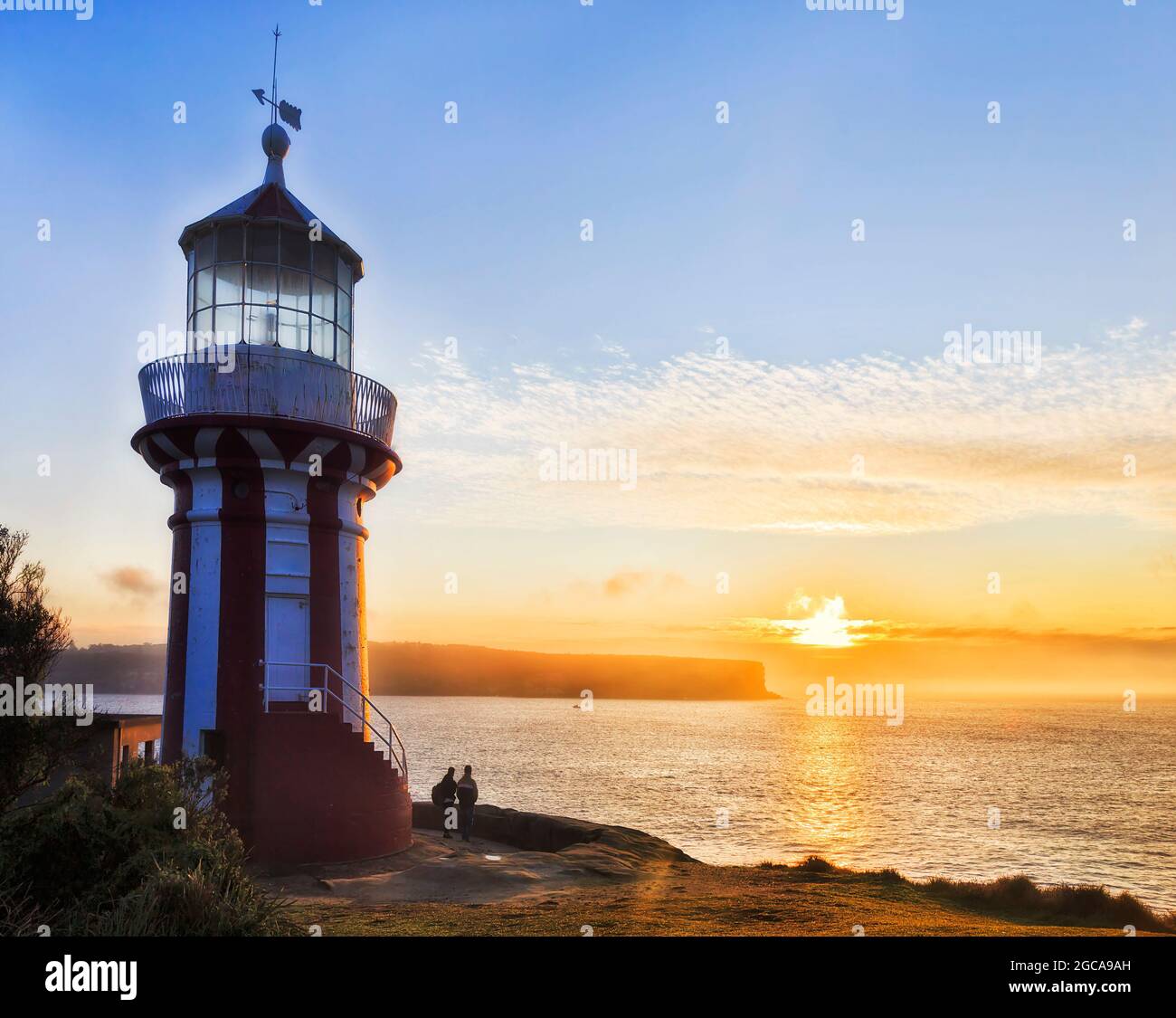 Striped red-white lighthouse at the entrance to Sydney Harbour on Pacific ocean coast - erected in 1858, scenic sunrise seascape . Stock Photo