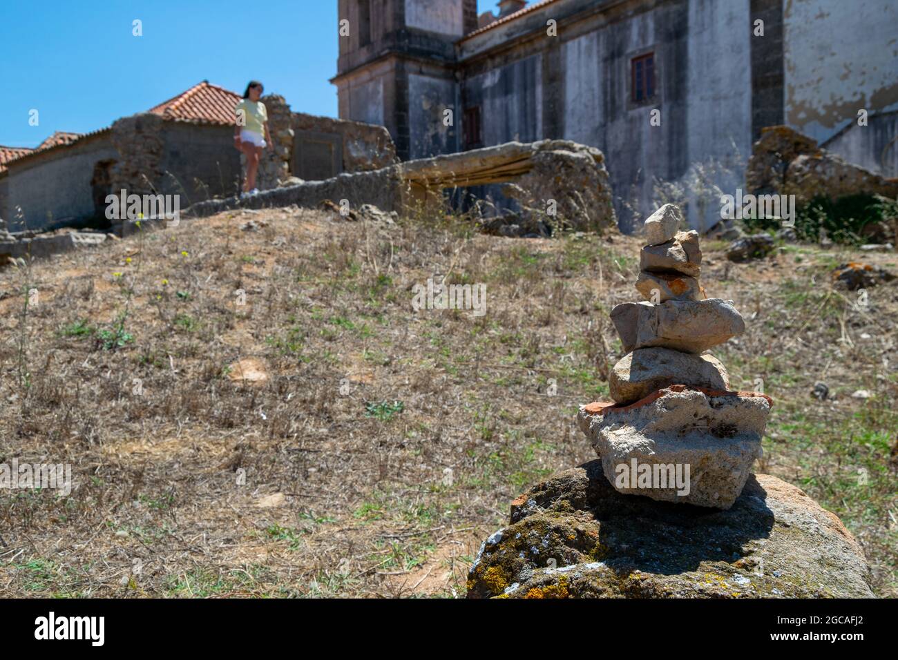 Zen rocks, vertically piled with young girl walking on the remains of a Sanctuary. Equilibrium rocks pile. Historical walks. Stock Photo