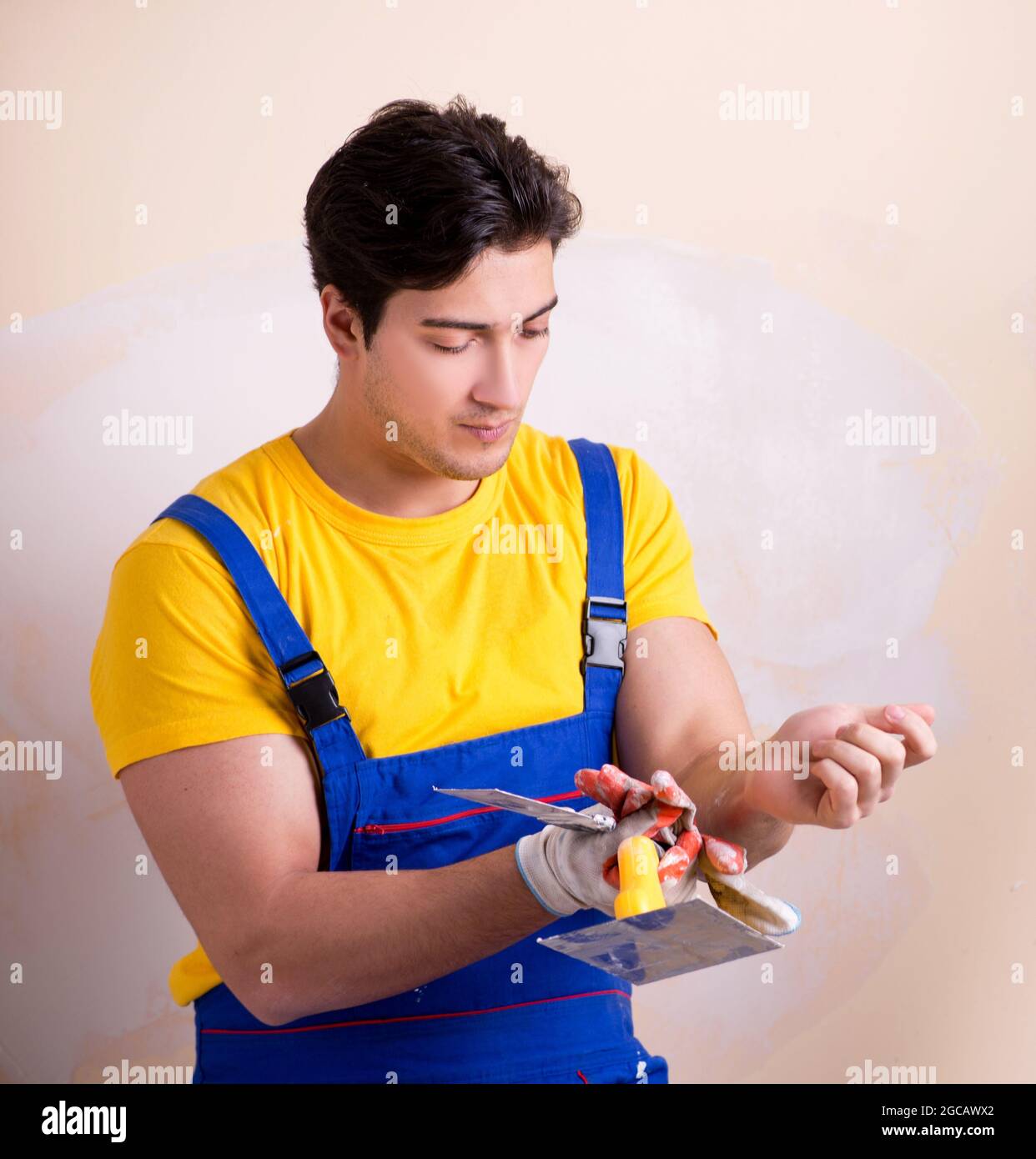 The young contractor employee applying plaster on wall Stock Photo