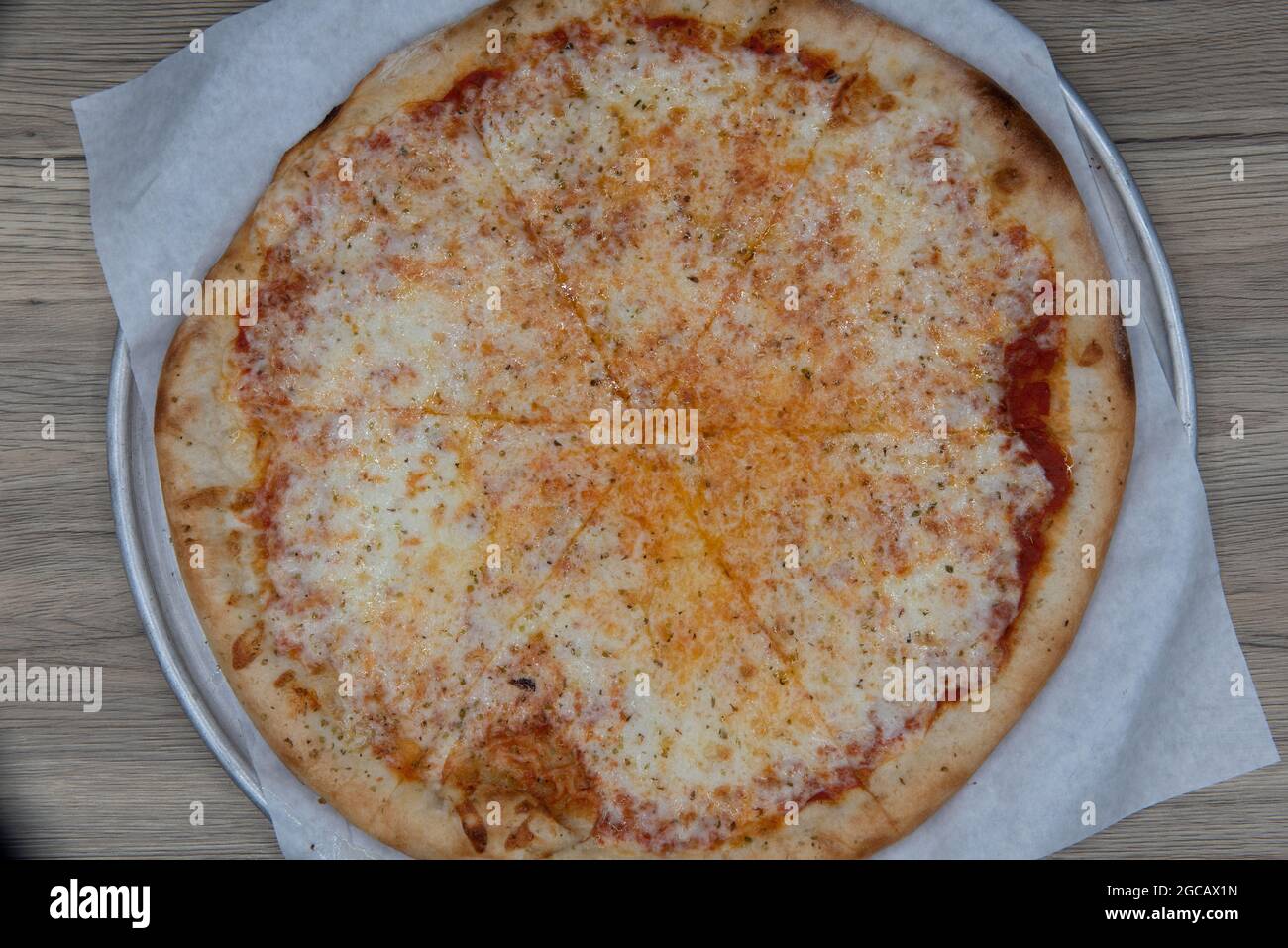 Overhead view of cheese pizza loaded with vegetable toppings and a crispy crust for a full family meal. Stock Photo