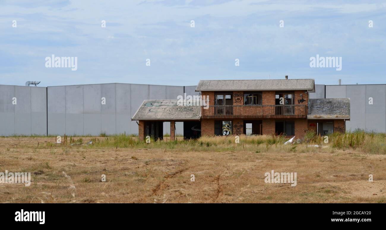 Abandoned farmhouse in the middle of an industrial estate shows the urbanisation of Australian farmland Stock Photo