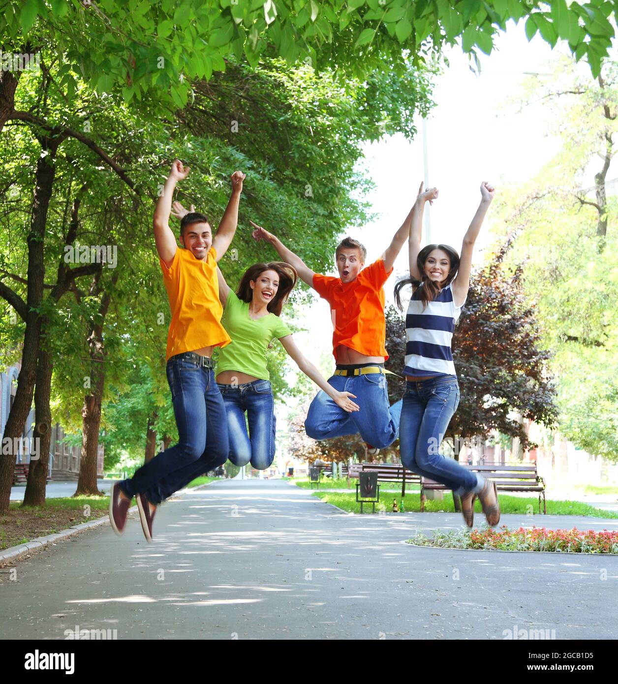 Happy group of young people jumping in park Stock Photo - Alamy