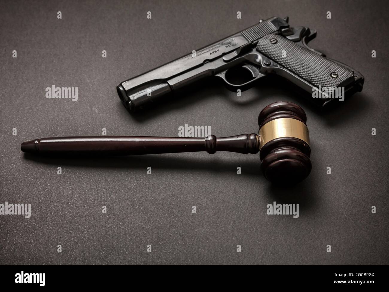 Law, crime, punishment concept. Judge gavel and a 9mm pistol on black