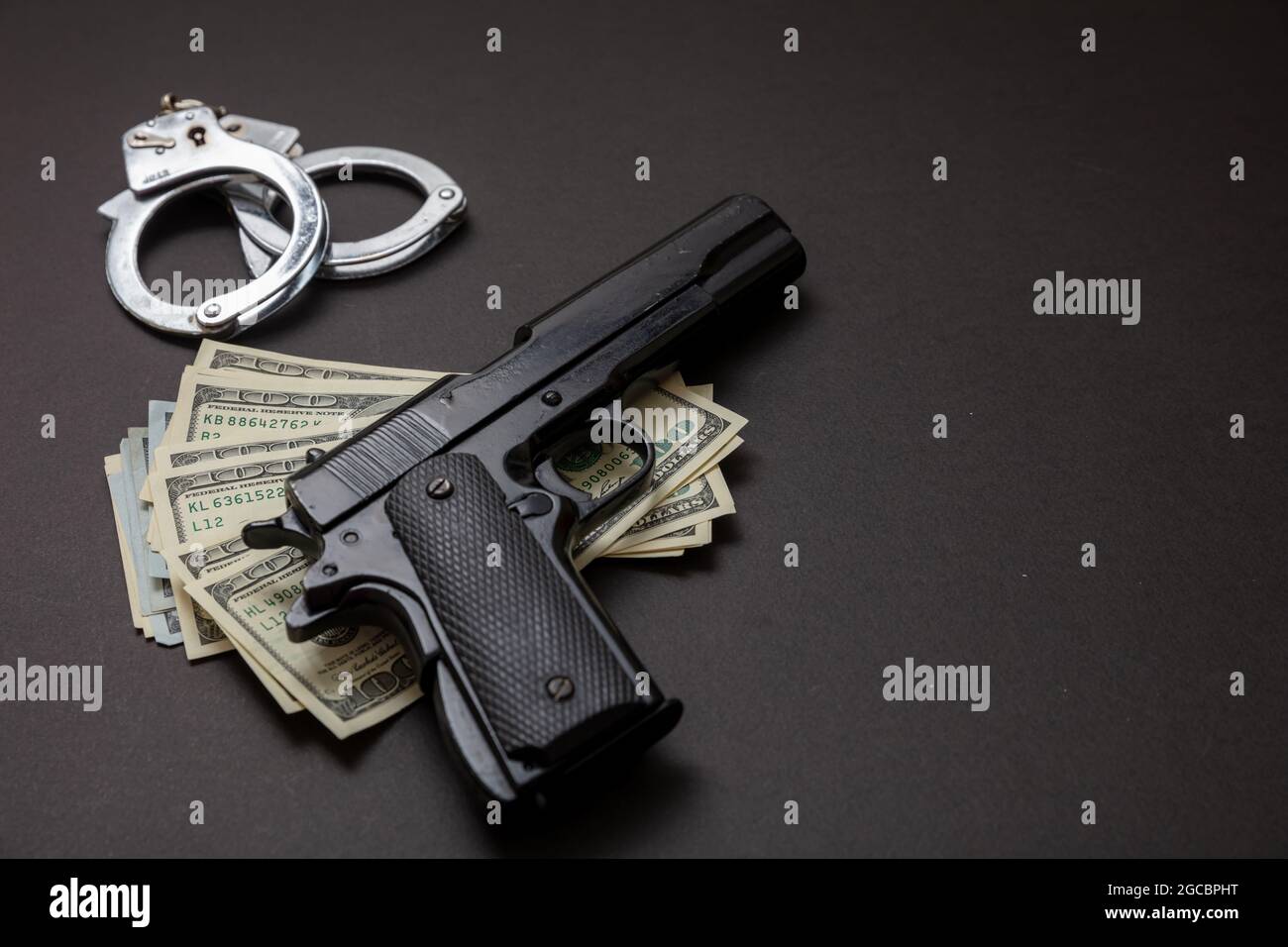 Crime and law concept. Pistol handgun 9 mm, hand cuffs and American dollar banknotes on black background. Criminal money and punishment, copy space, t Stock Photo