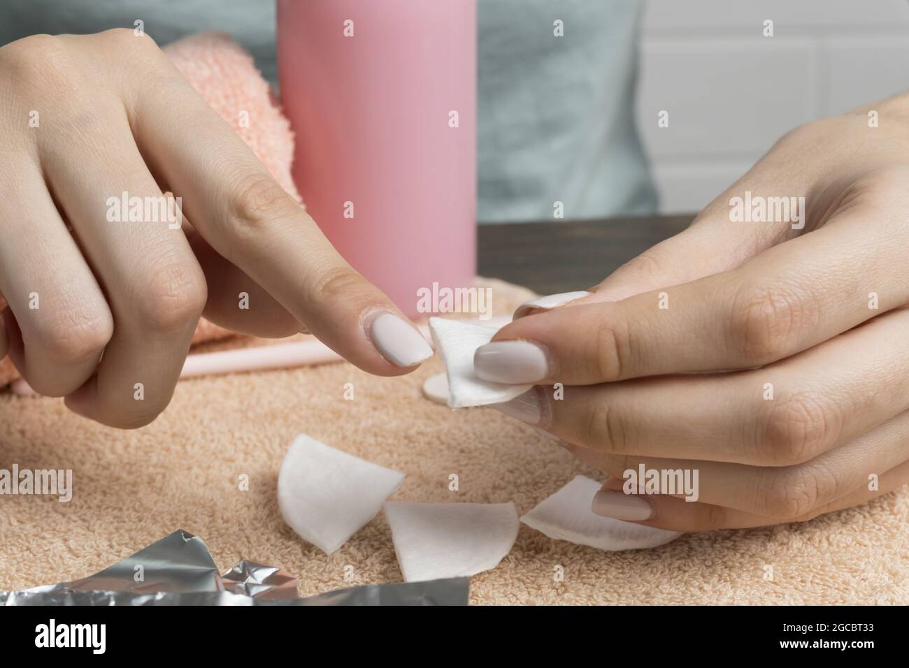 Removing gel Polish from nails. Woman pours remove liquid on a cotton pad, puts it on a nail and
