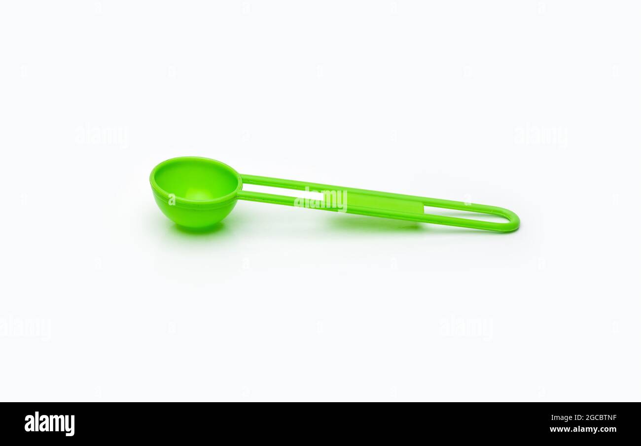Green measuring plastic spoon on isolated white background Stock Photo