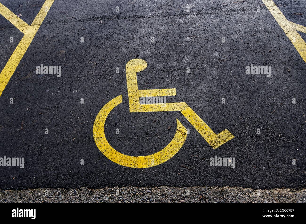 Disabled parking is marked with a yellow disabled sign painted on the road Stock Photo