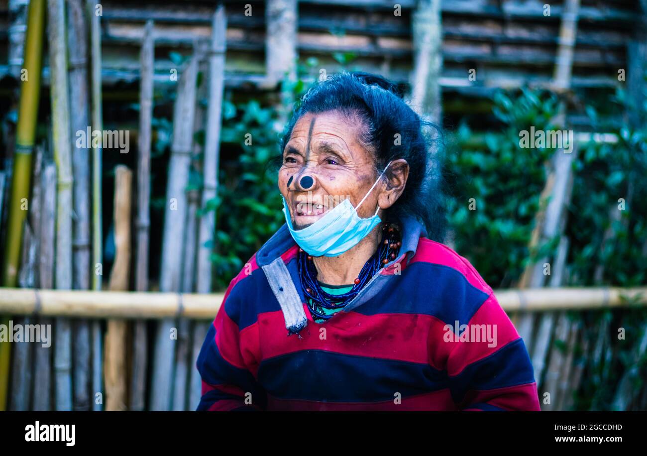 apatani tribal women facial expression with her traditional nose lobes and blurred background image is taken at ziro arunachal pradesh india. it is on Stock Photo