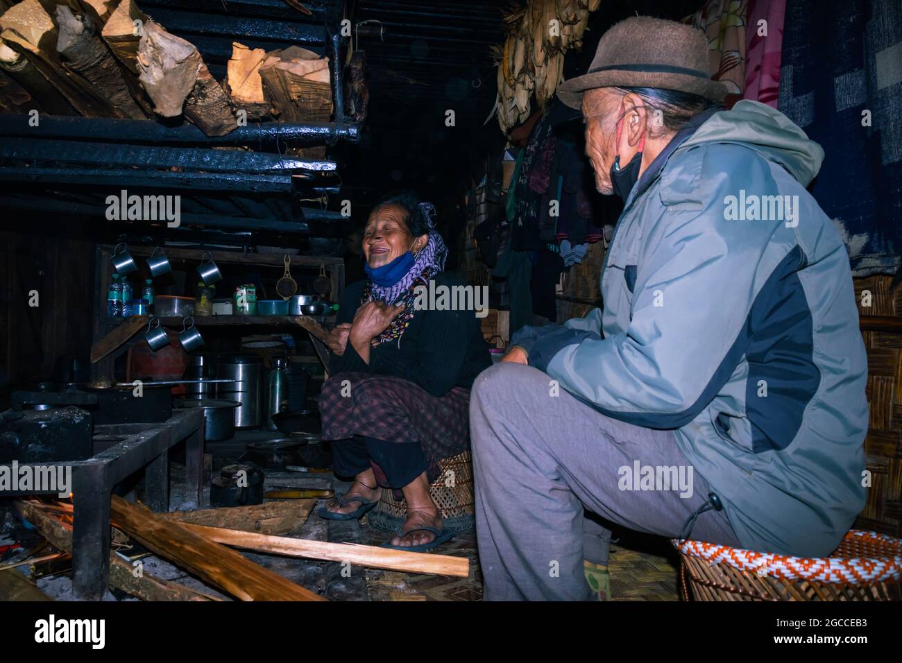 apatani tribal couple at their home near fire place cooking food at evening from flat angle image is taken at ziro arunachal pradesh india. it is one Stock Photo