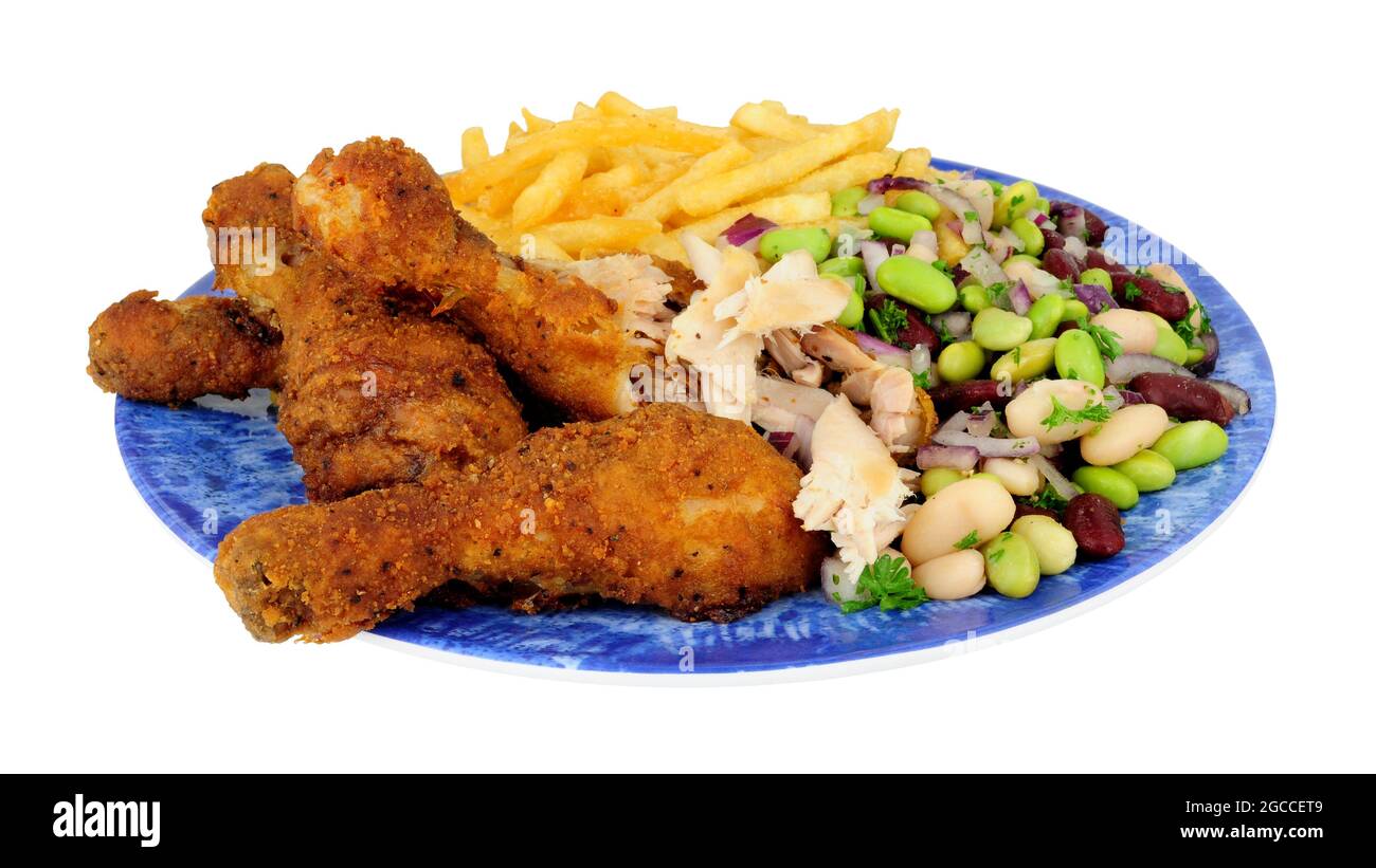 Southern fried chicken drumsticks meal with three bean salad and French fries isolated on a white background Stock Photo