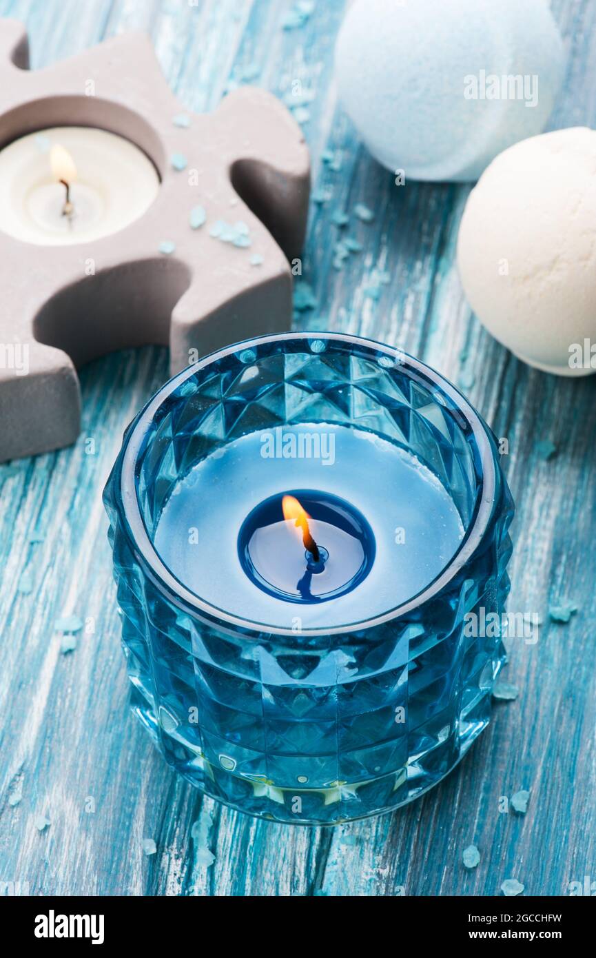 SPA still life, closeup of blue lit candle and bath bombs on wooden background Stock Photo