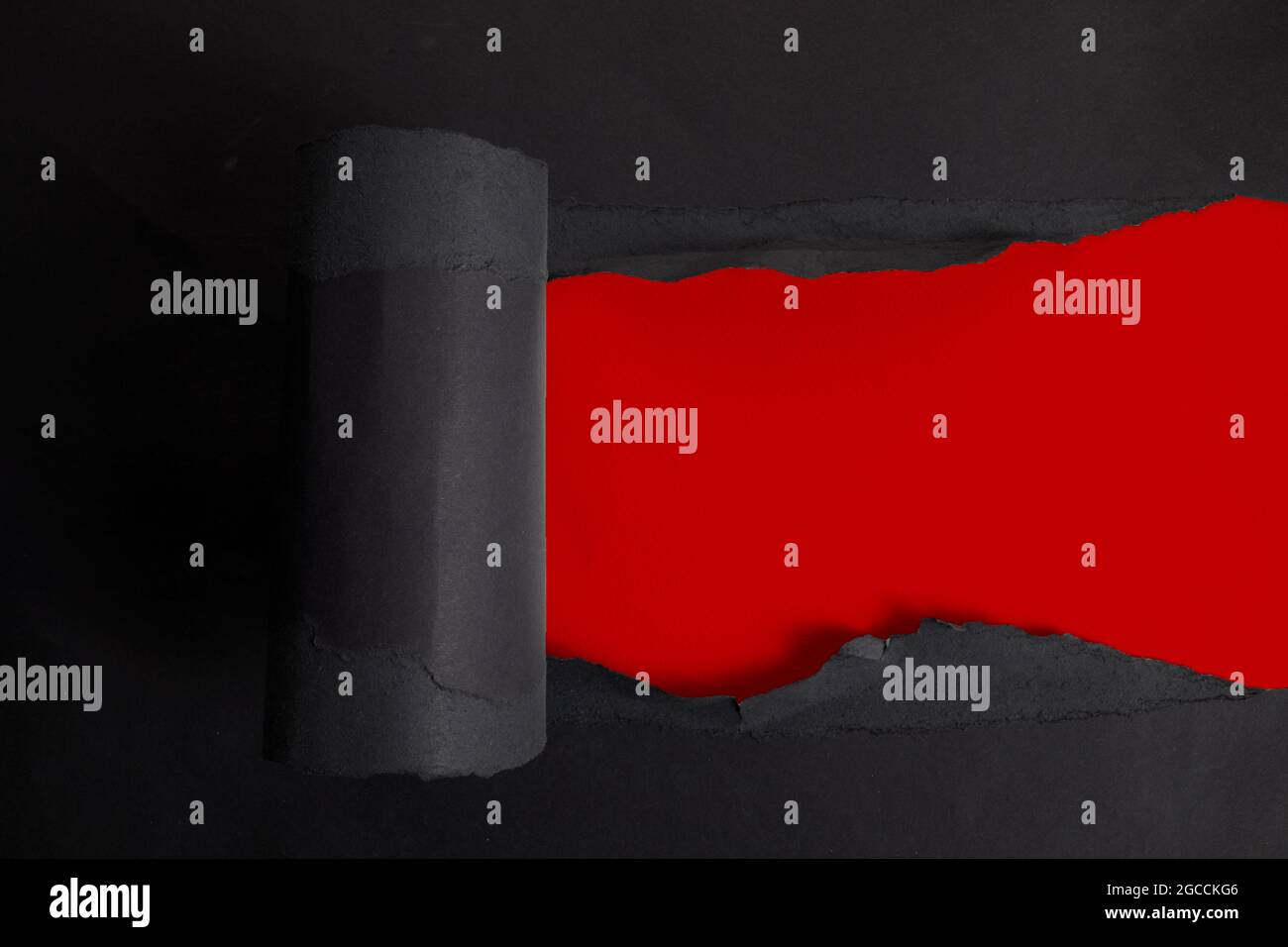 Torn black paper on red background. Top view Stock Photo