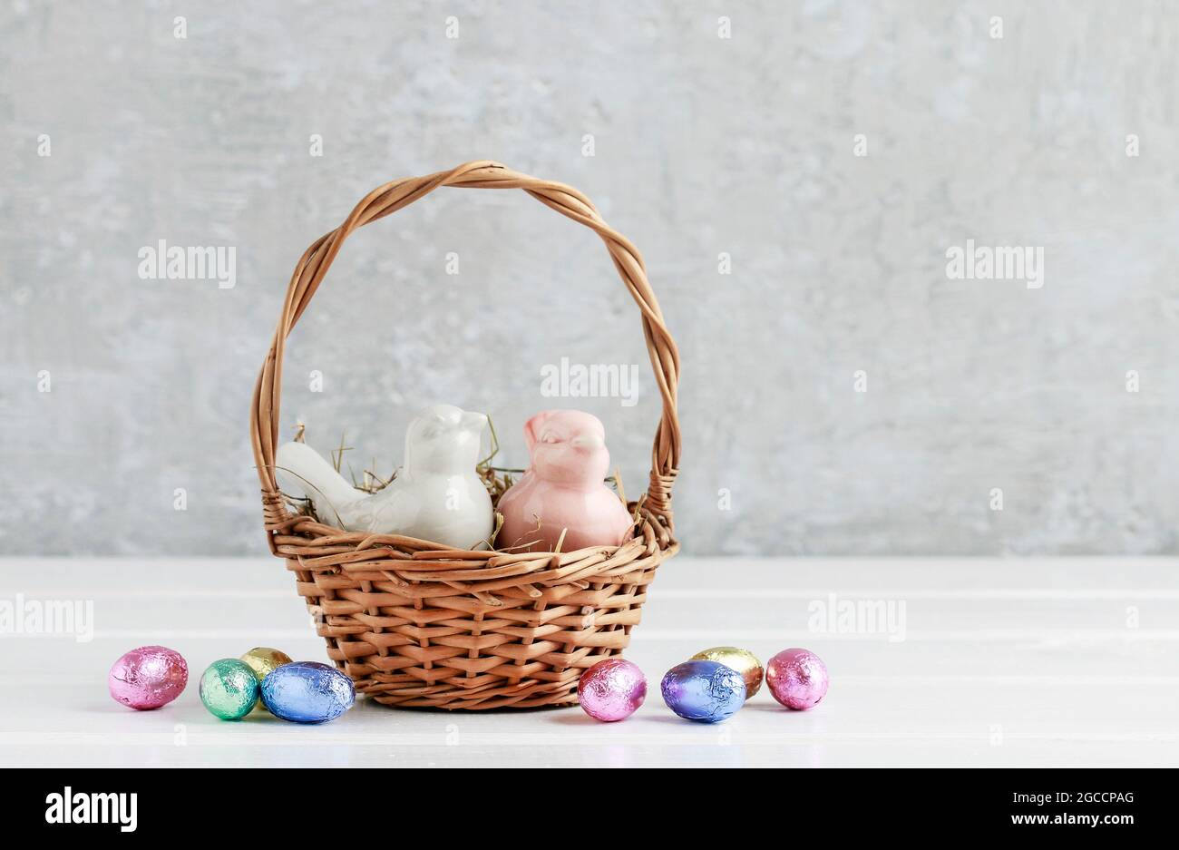 Two ceramic birds in wicker Easter basket. Eggs around, grey stone  background. Festive decor Stock Photo - Alamy