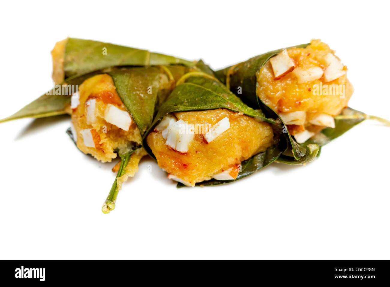 Traditional steamed ripe palmyra palm fruit cake wrapped with jackfruit leaves and sprinkled with coconut pieces. Steamed palmyra palm cake in isolate Stock Photo