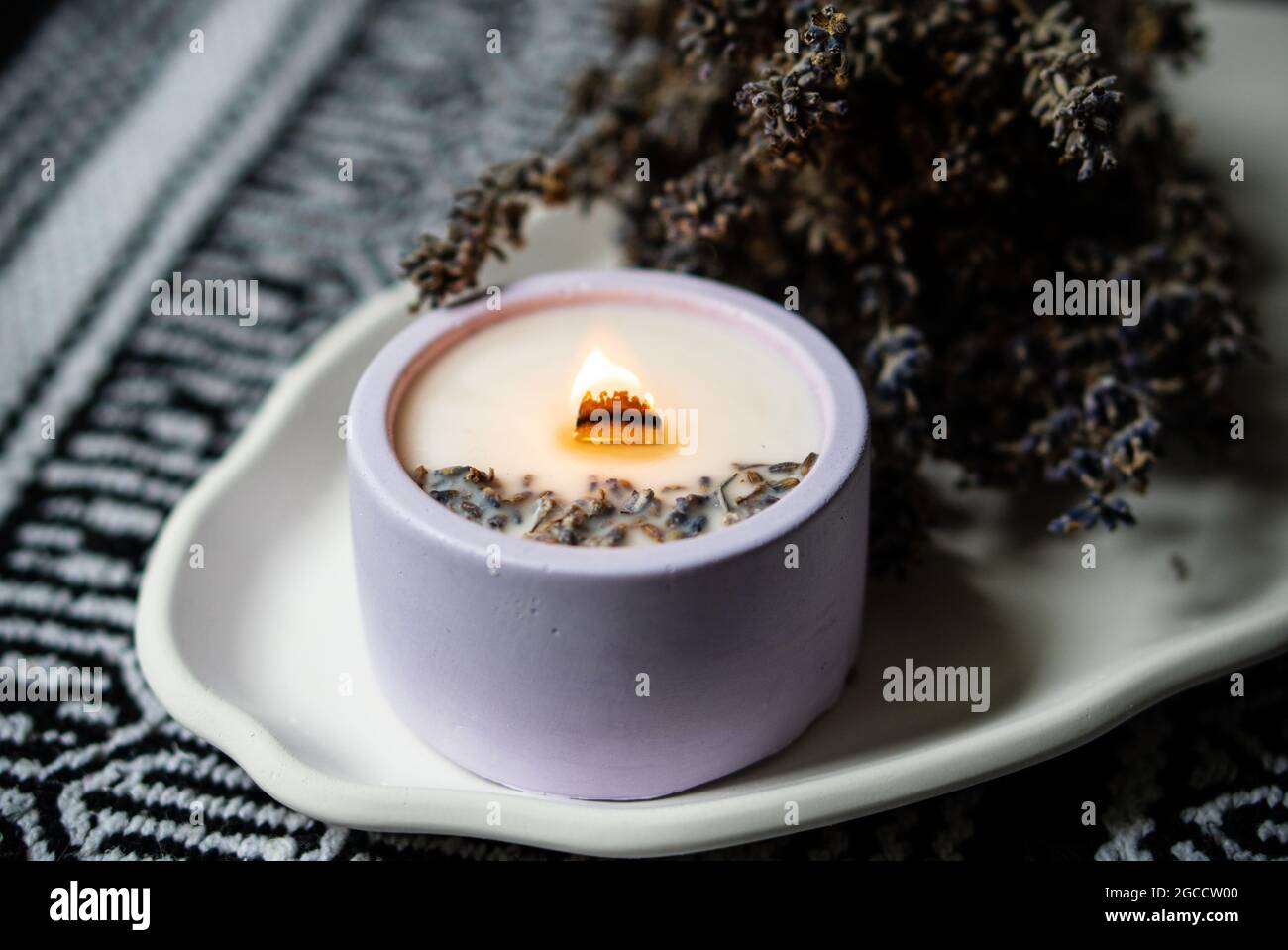 Burning lavender scented candle with wooden wick and bunch of dried