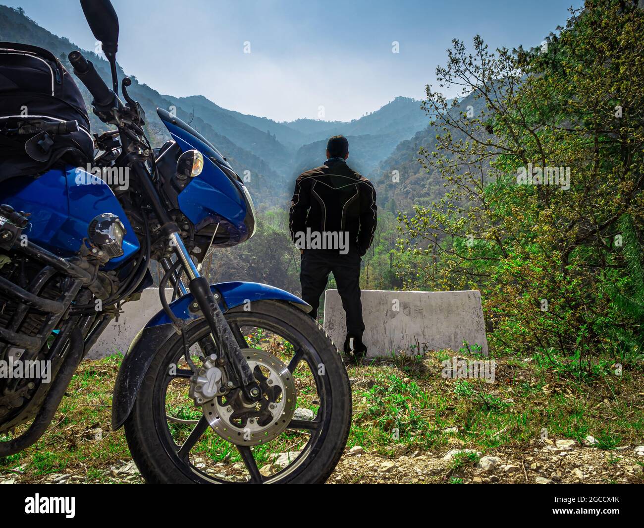 man motorcyclist with his motorcycle and beautiful natural view at morning image is taken at shergaon arunachal pradesh india. Stock Photo