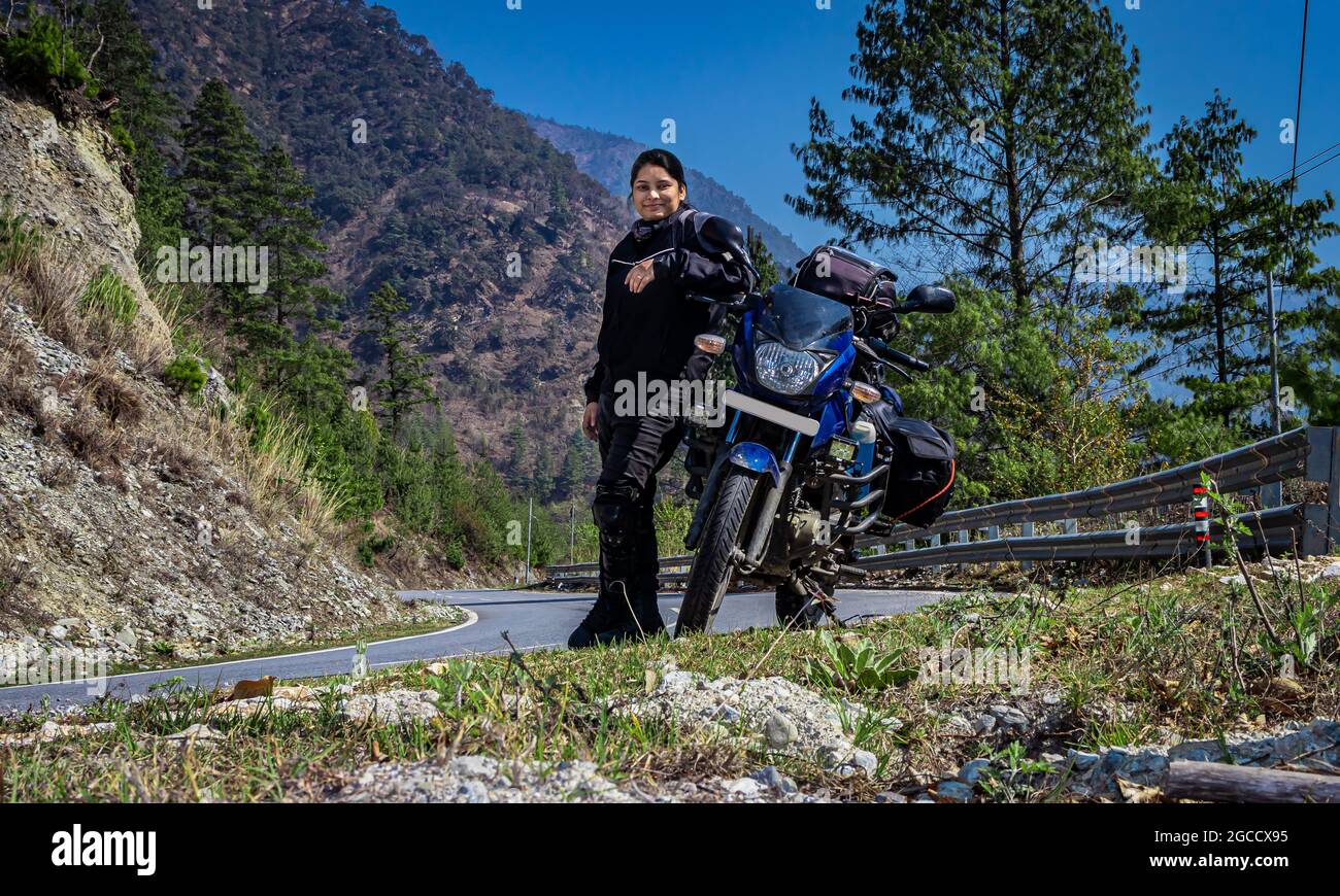 girl motorcyclist with her motorcycle and beautiful natural view at morning image is taken at shergaon arunachal pradesh india. Stock Photo