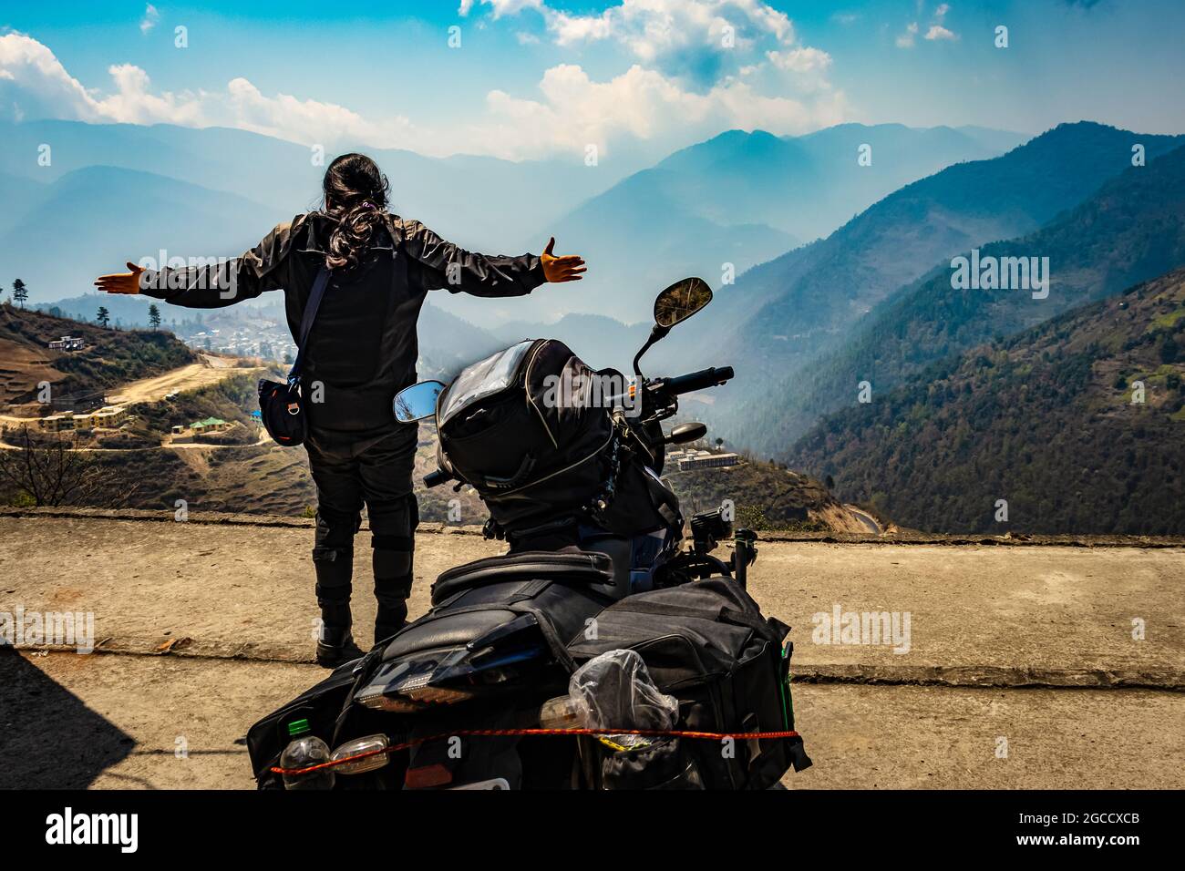 girl motorcyclist with her loaded motorcycle and pristine natural view at morning image is taken at bomdila arunachal pradesh india. Stock Photo