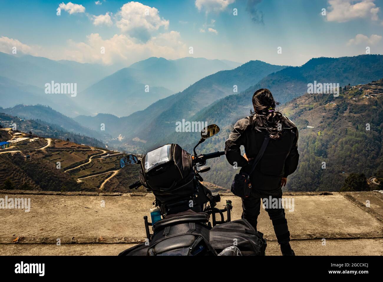 girl motorcyclist with her loaded motorcycle and pristine natural view at morning image is taken at bomdila arunachal pradesh india. Stock Photo