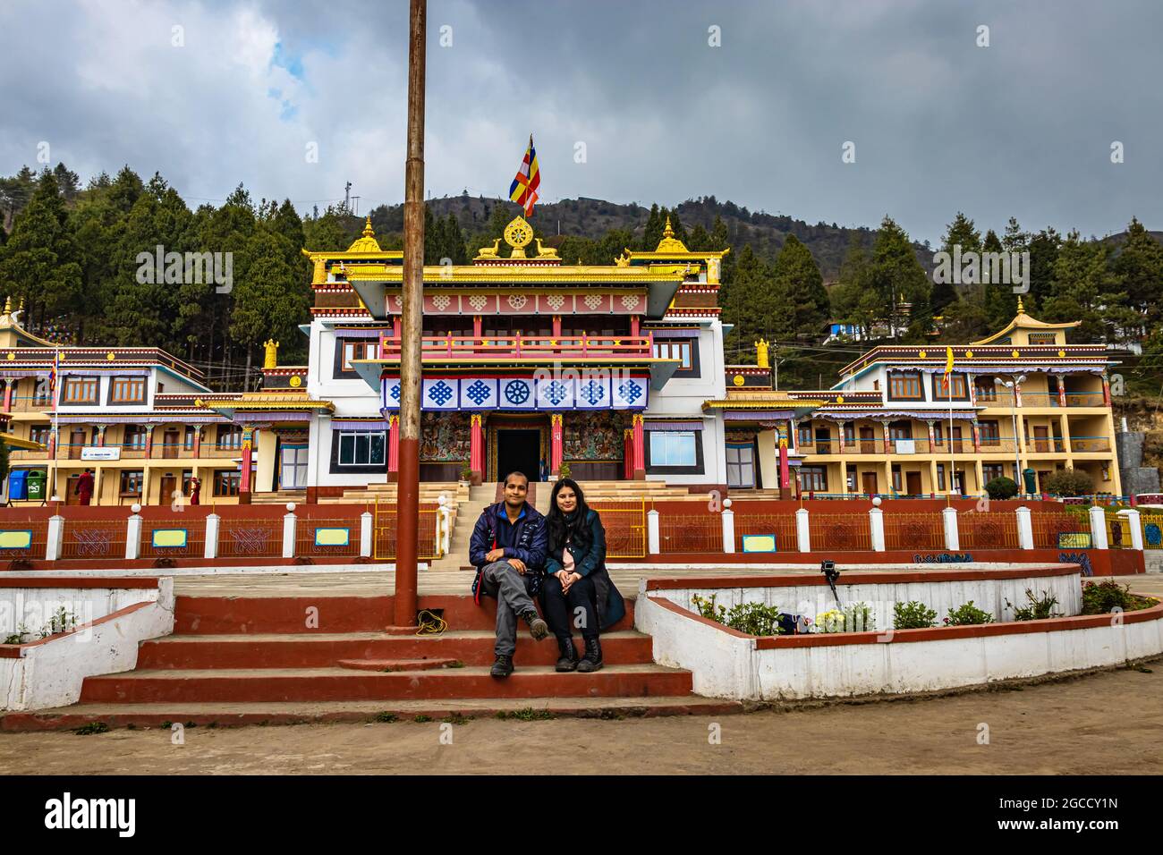 young couple sitting in front of ancient buddhist colorful monastery at day image is taken at bomdila monastery arunachal pradesh india. Stock Photo