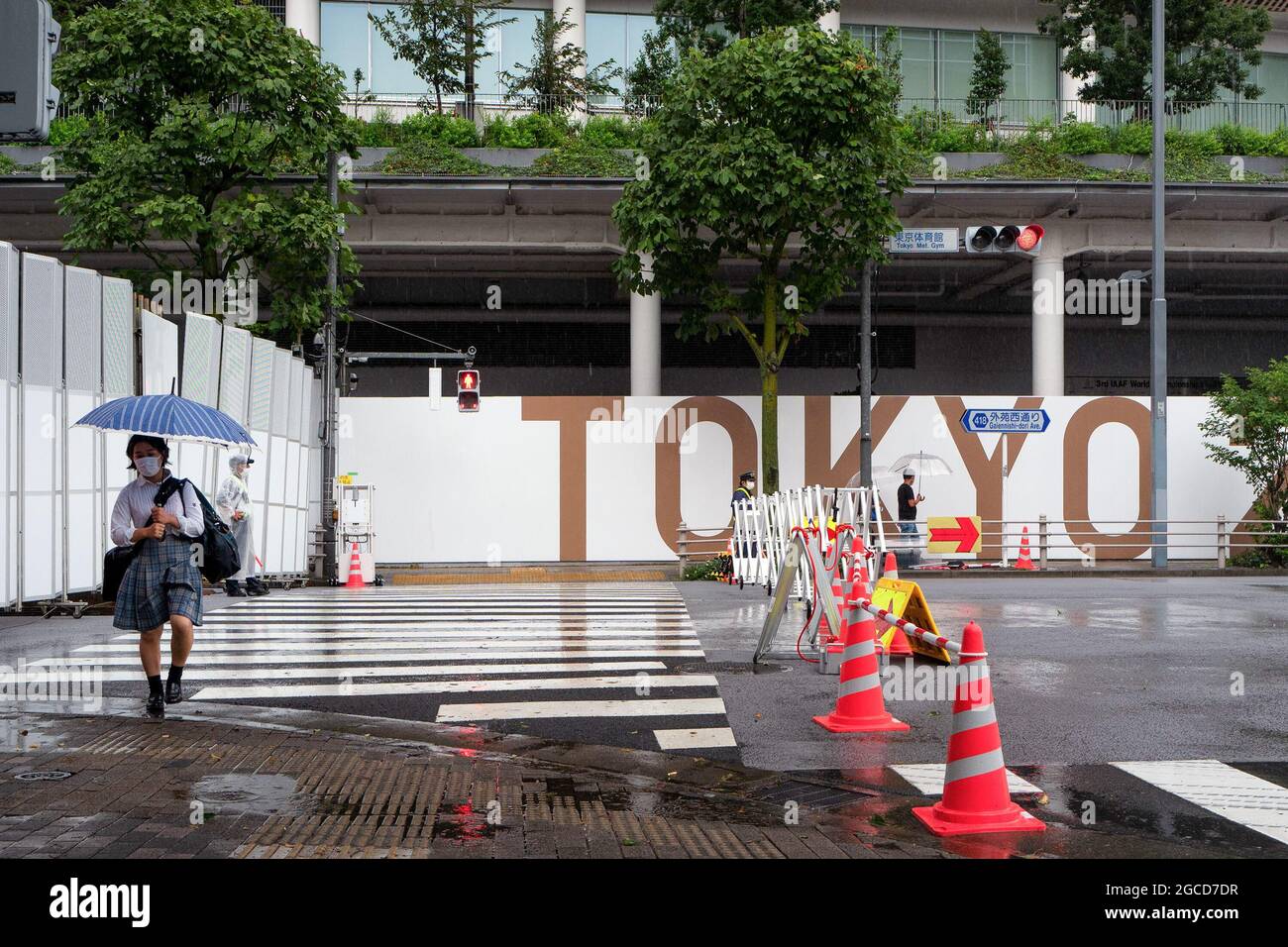 A Japanese High school girl with an umbrella walks past the Tokyo National Stadium on the last day of Tokyo Olympics Games. Stock Photo
