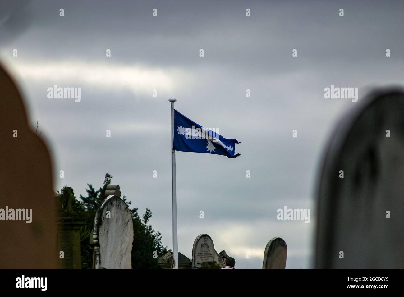 Eureka flag flying in the wind on a gloomy overcast day in the old Ballarat cemetery Stock Photo