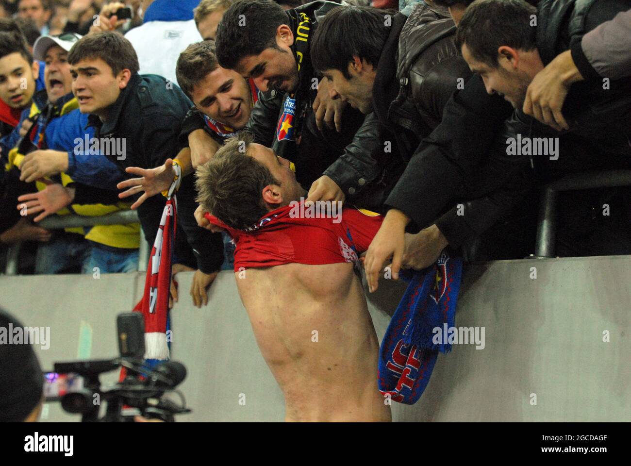 BUCHAREST, ROMANIA - NOVEMBER 3, 2011: FCSB fans try to take the shirt off from Novak Martinovic after the UEFA Europa League Group J game between FCSB and Maccabi Haifa at National Arena. Stock Photo