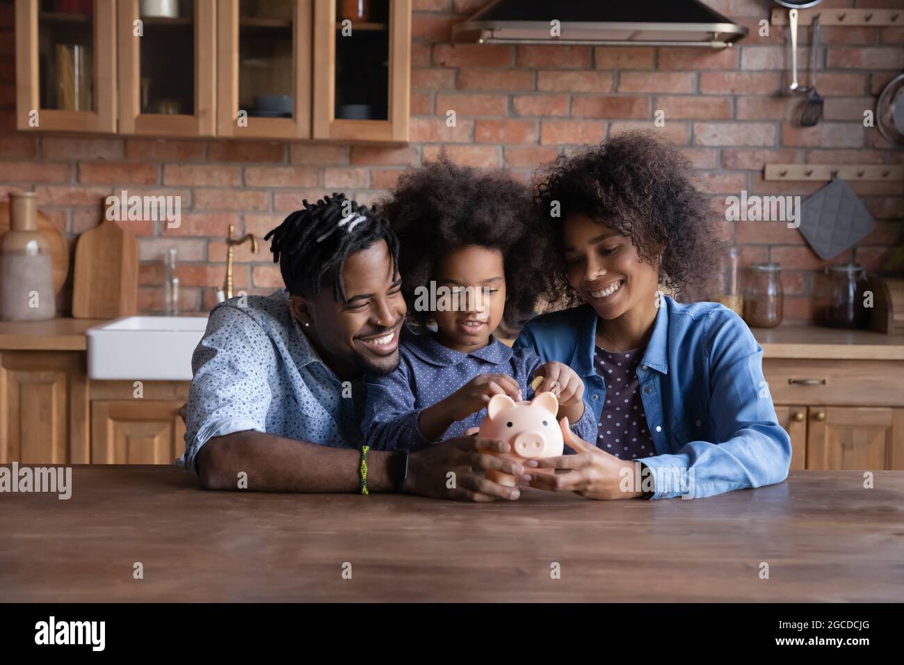 Happy ethnic family with kid save money in piggybank Stock Photo