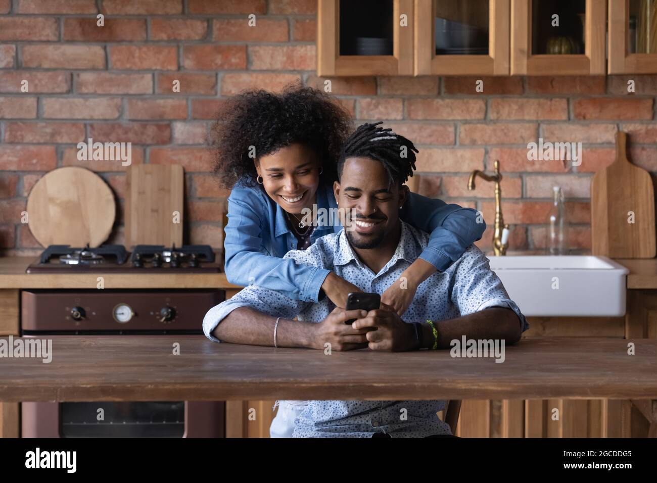 Smiling young biracial couple use cellphone together Stock Photo