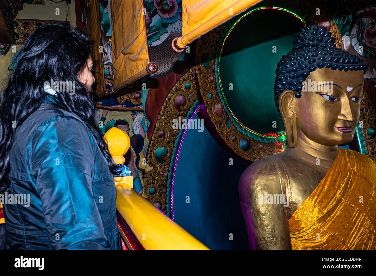 huge buddha golden statue decorated with religious flags and girl standing near by from flat angle image is taken at tawang monastery arunachal prades Stock Photo