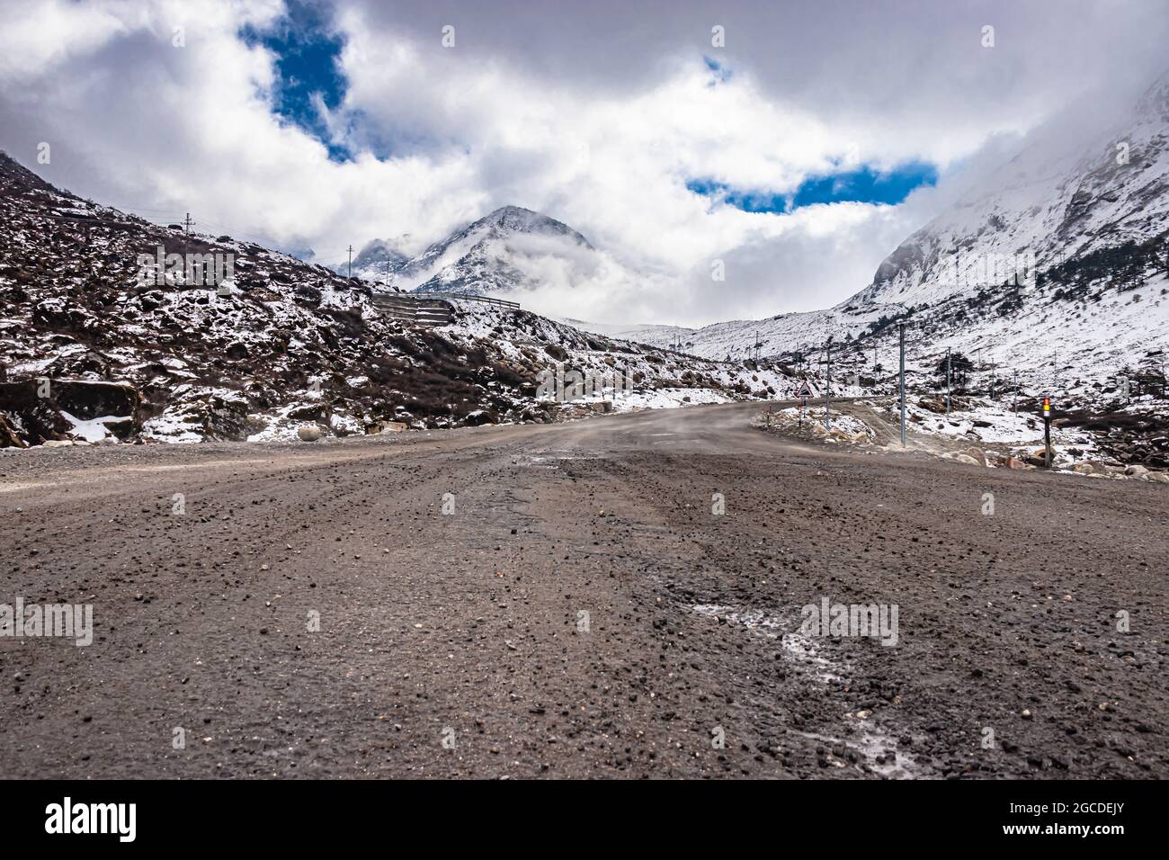 isolated tarmac road with snow cap mountain background and amazing sky at morning image is taken at sela pass tawang arunachal pradesh. Stock Photo