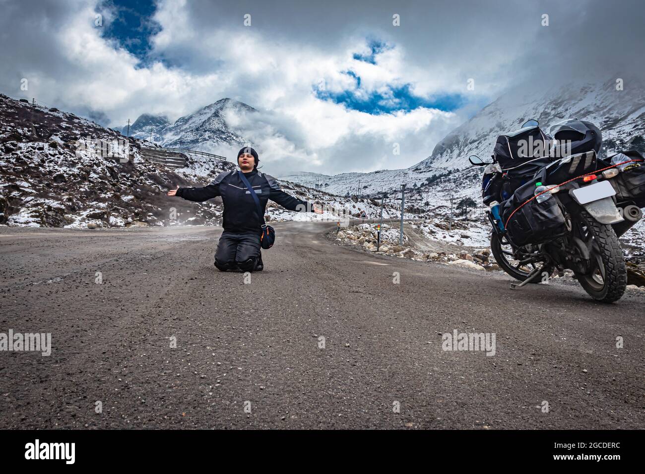 girl solo traveler at isolated tarmac road with snow cap mountains in background at morning image is taken at sela pass tawang arunachal pradesh india Stock Photo