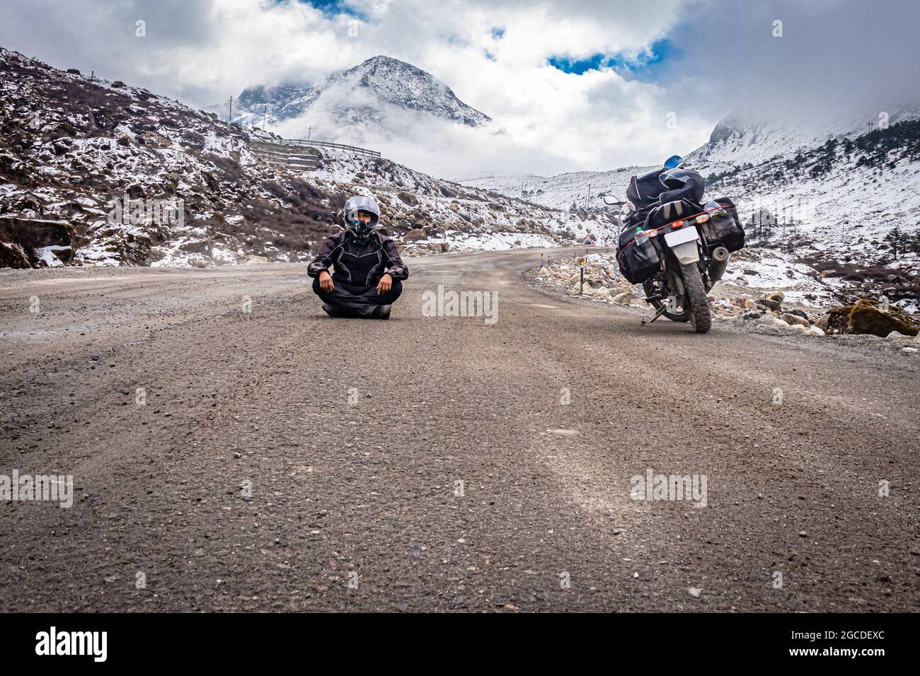 man solo traveler at isolated tarmac road with snow cap mountains in background at morning image is taken at sela pass tawang arunachal pradesh india. Stock Photo