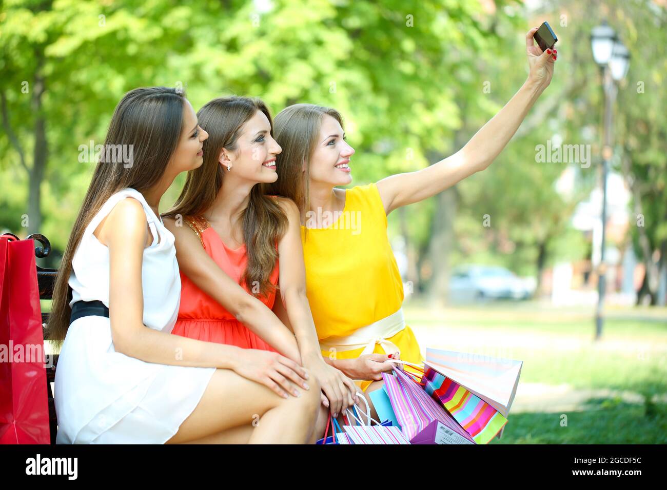 Three beautiful young woman taking picture in summer park Stock Photo ...