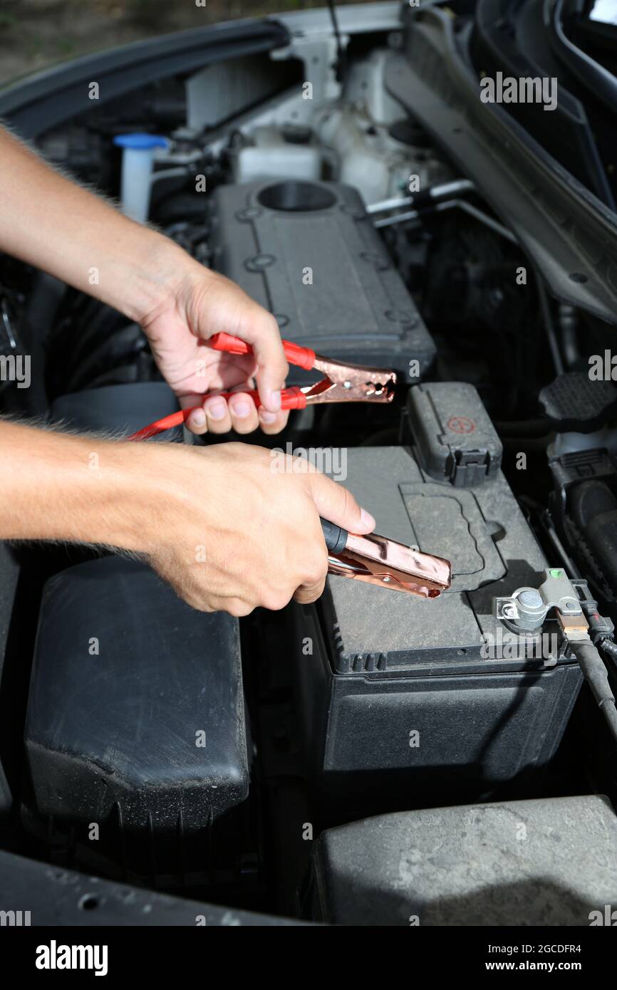 Car mechanic uses battery jumper cables to charge dead battery Stock Photo Alamy