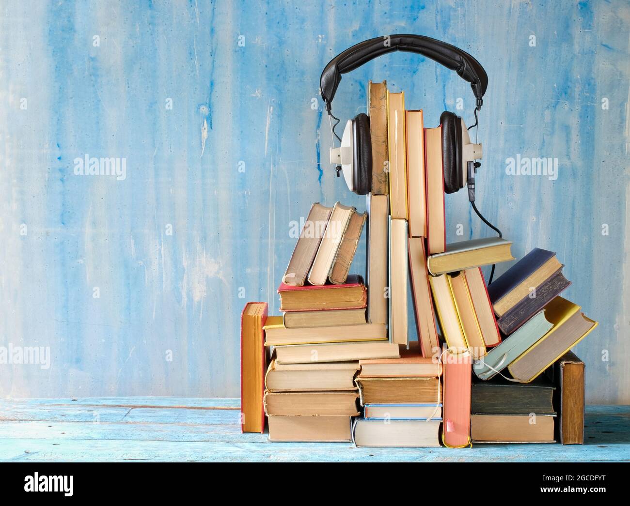 audio book concept with large heap of books and vintage headphones, good copy space Stock Photo