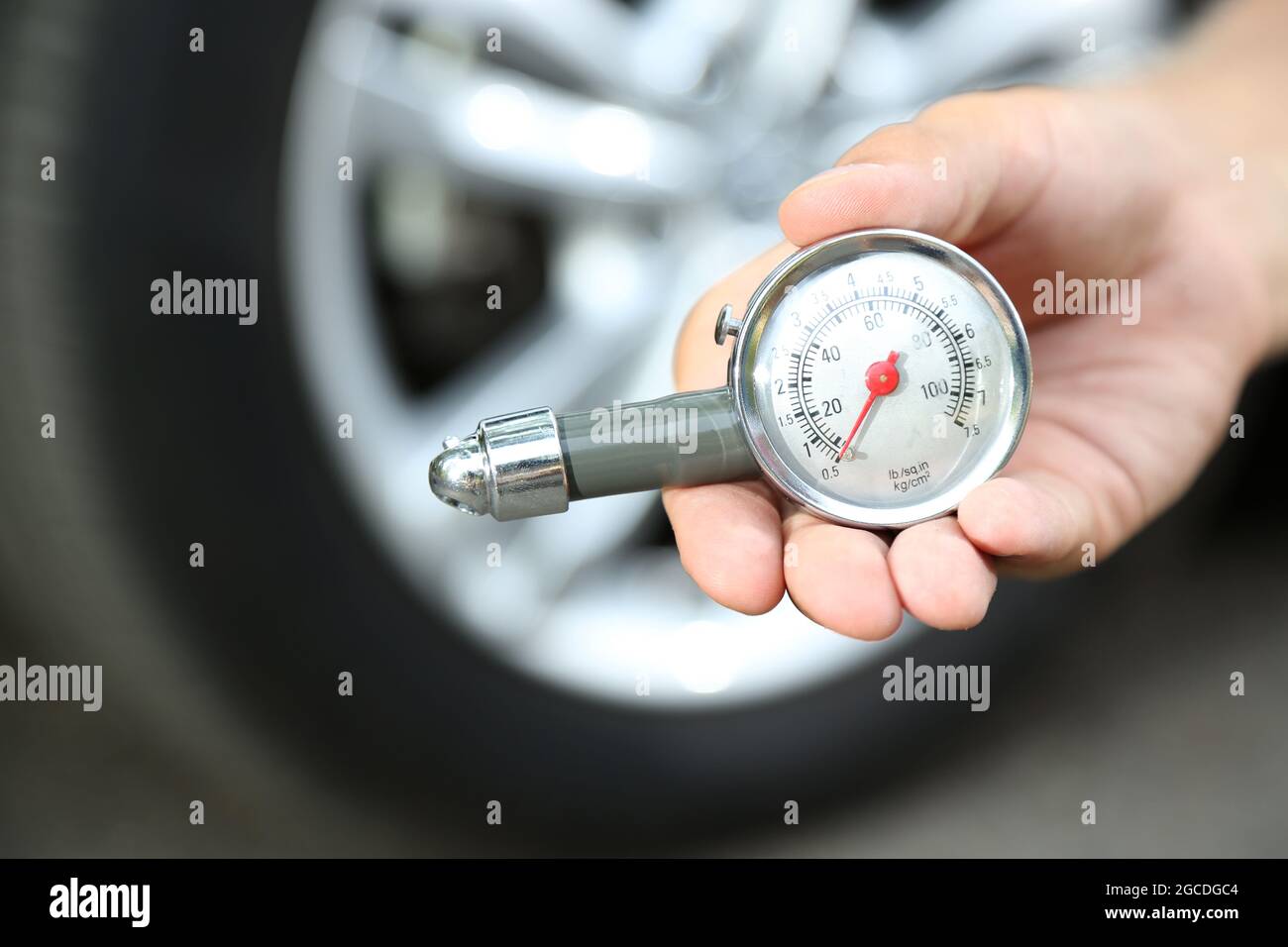 Hand holding pressure gauge for car tyre pressure measurement Stock