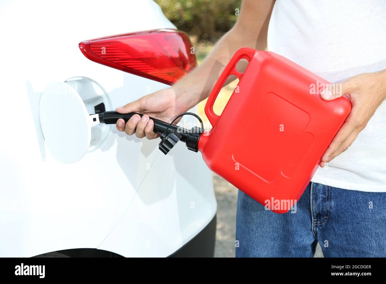 Man pouring fuel into gas tank of his car from red gas canister Stock