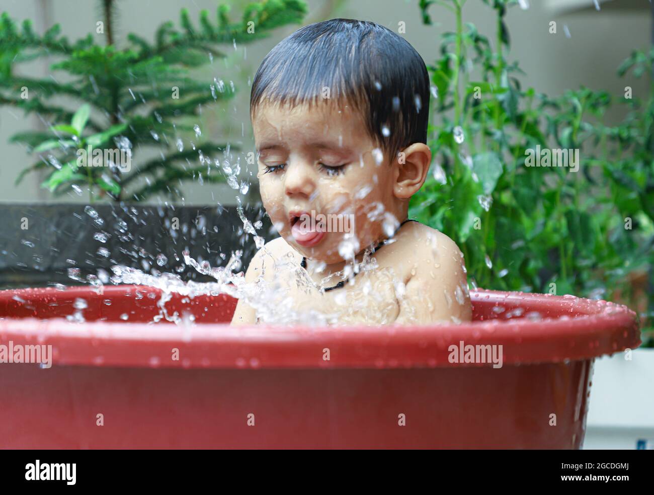 portrait of a cute indian baby girl with drops of water on her face during shower. Stock Photo