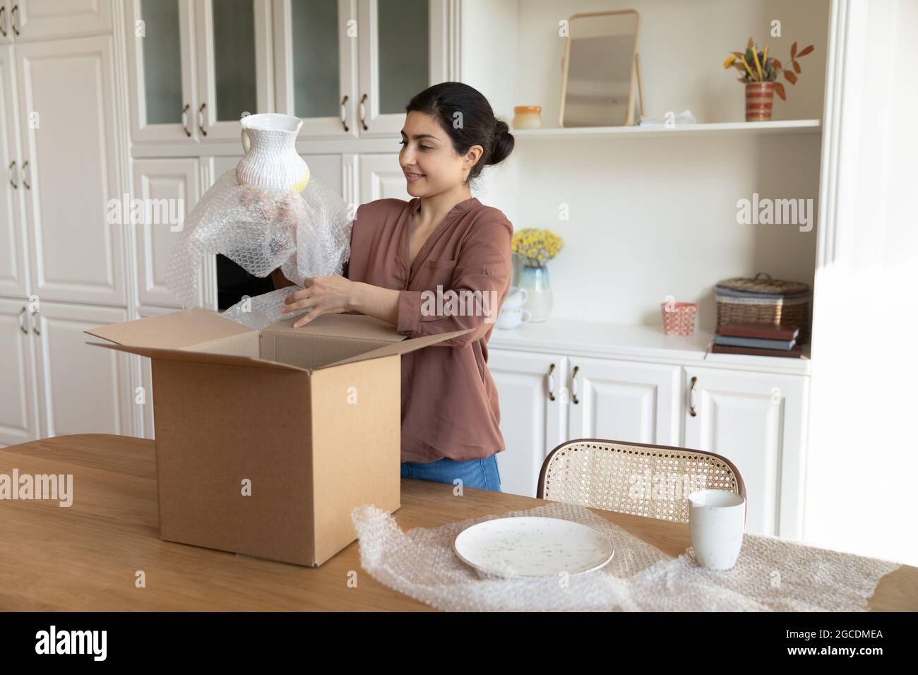 Happy Indian woman unpack box with tableware order Stock Photo