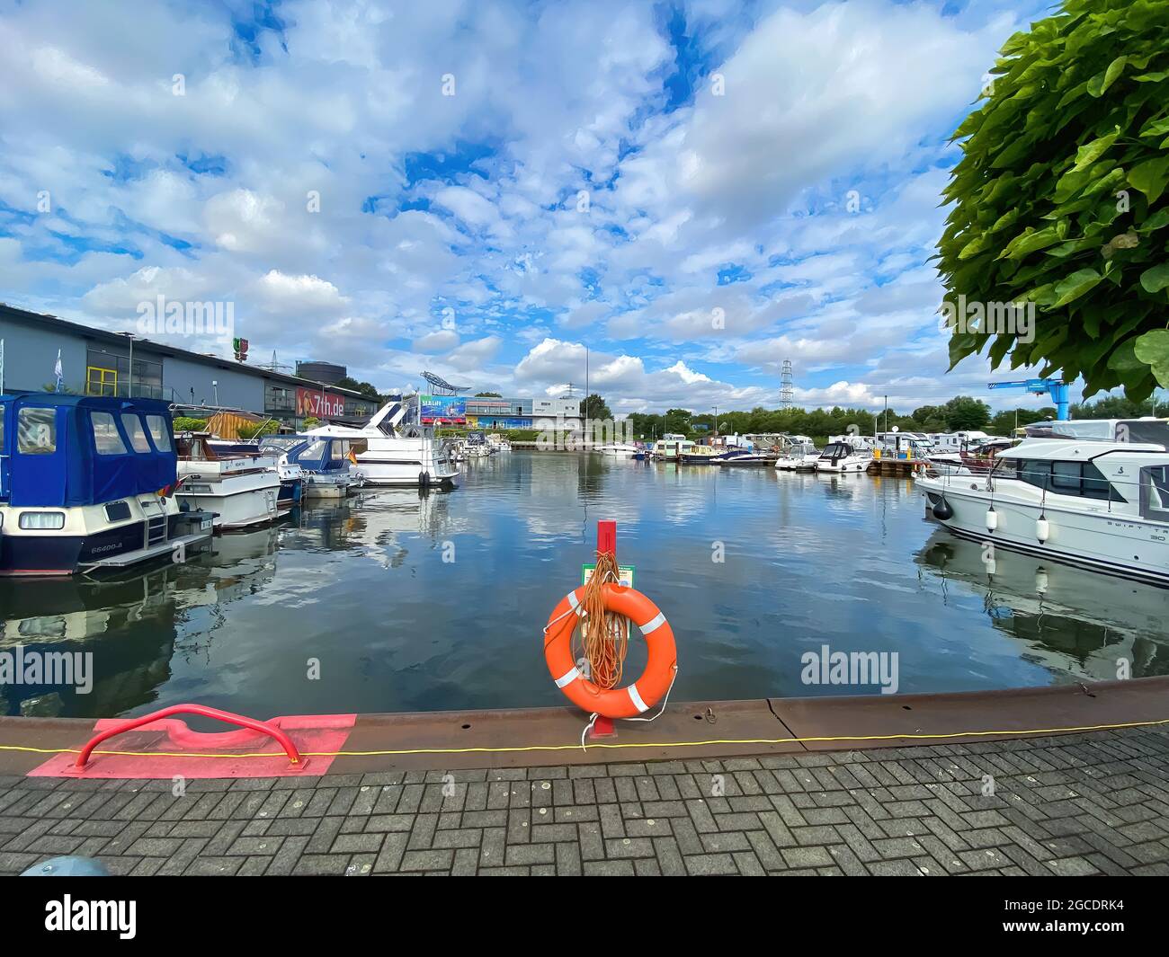 Oberhausen (Centro), Germany - July 9. 2021: View on inland port with boats in summer with orange lifebelt, sealife building background Stock Photo