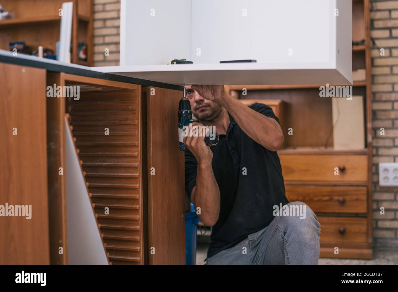 Worker drilling a hole under a board in a workshop. Stock Photo