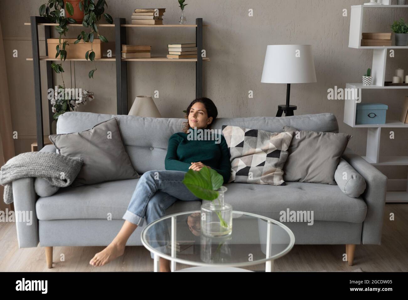 Satisfied woman relaxing on cozy couch in modern living room Stock Photo