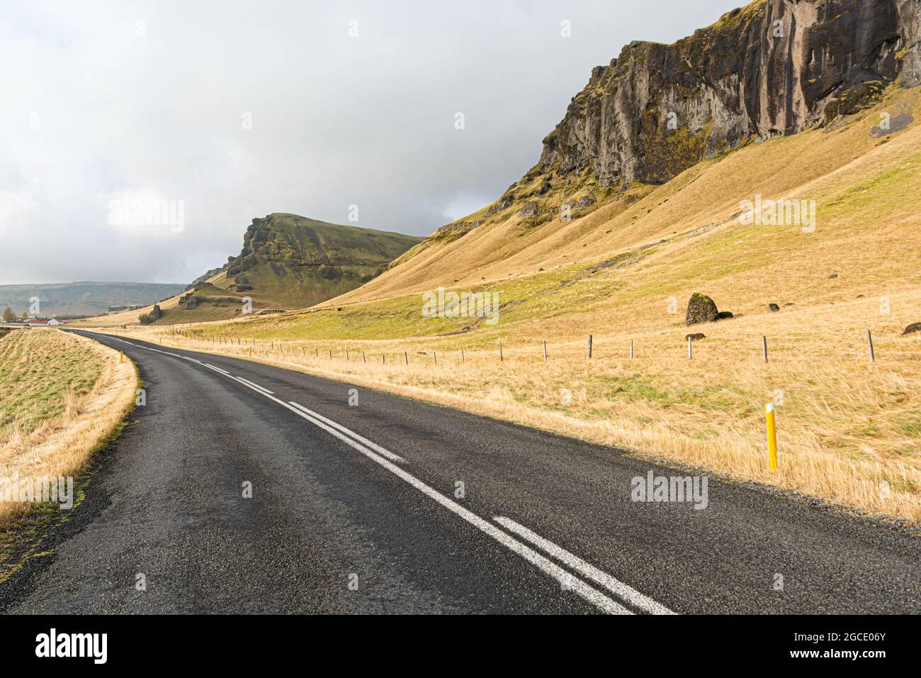 A natural view of a paved country road on the side of rocky mountains in Iceland Stock Photo