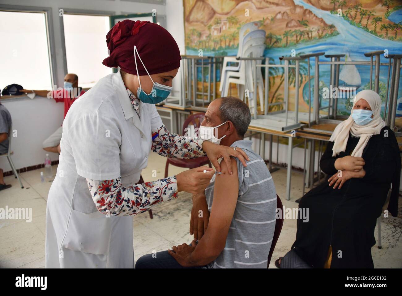 A health worker administers the AstraZeneca vaccine to a Tunisian man at Oued Ellil high school in Manouba. The national Covid-19 vaccination day for people aged 40 and above started this Sunday, August 8, 2021, in various parts of Tunisia. (Photo by Jdidi Wassim / SOPA Images/Sipa USA) Stock Photo