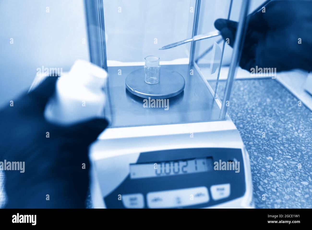 Scientist weighing chemicals by digital scales in grams in chemical laboratory. Blue toning Stock Photo