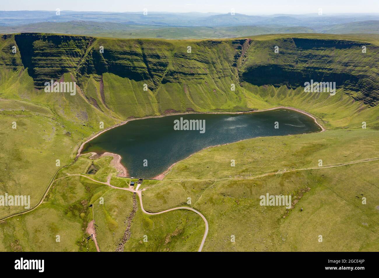 Aerial view of a lake formed at the base of green mountains (Llyn y Fan Fach, Brecon Beacons, Wales) Stock Photo